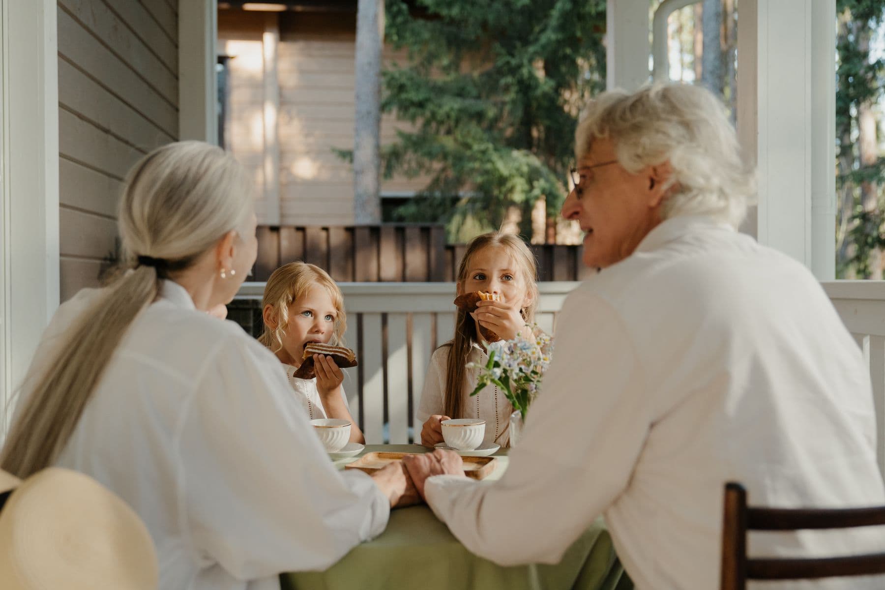 Grandparents and two grandchildren at a patio table, mid-conversation
